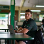 Rugby player sitting at a table in front of a laptop